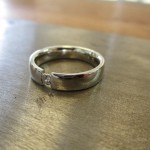 Ein schmaler silberner Ring mit einem kleinen Einschnitt in der Front. Im Einschnitt sitzt ein kleiner Schmuckstein.
