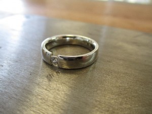 Ein schmaler silberner Ring mit einem kleinen Einschnitt in der Front. Im Einschnitt sitzt ein kleiner Schmuckstein.