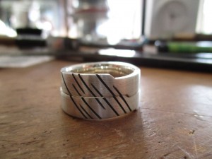 Silberne Ringe mit vertikalen, schwarzen Einkerbungen.