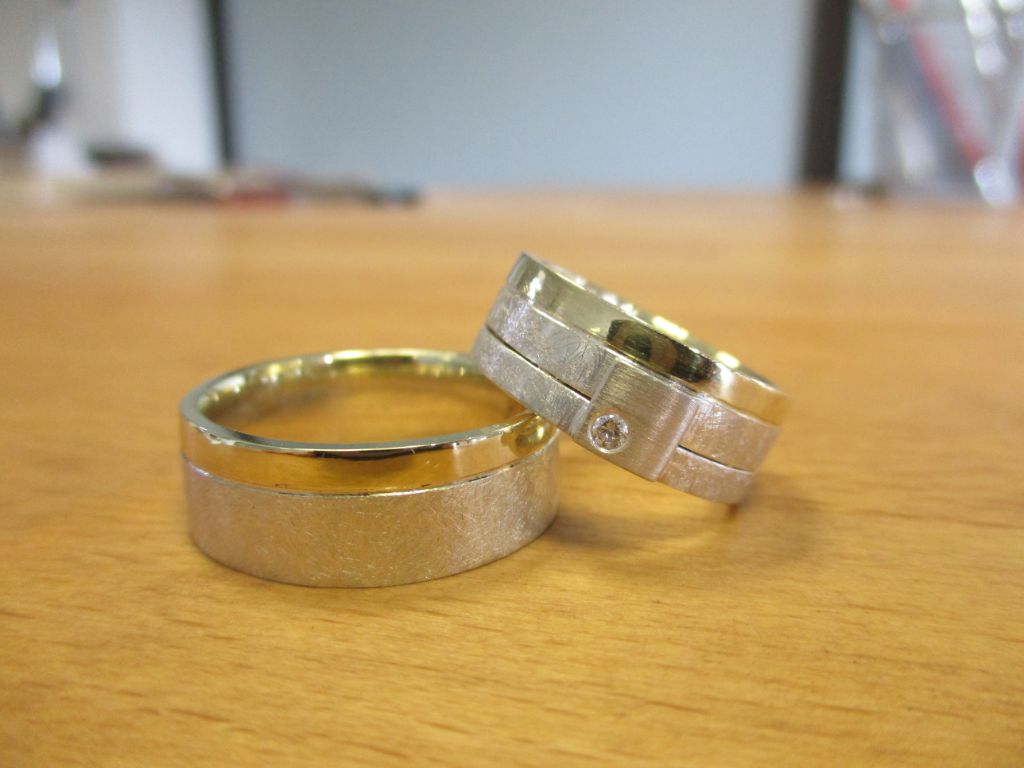 Silberne Ringe mit gebürsteter Textur und einem gedrittelten Rücken entlang der Länge des Rings. Die rechten zwei Drittel sind Gold an Stelle von Silber.